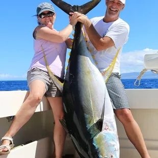 Happy customers holding up a big Yellowfin Tuna