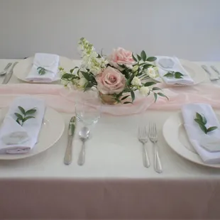Soft and romantic wedding table setting featuring a blush pink table runner and gold accents.