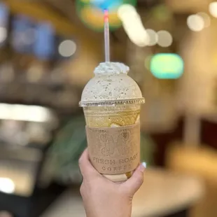 a hand holding a cup of iced coffee