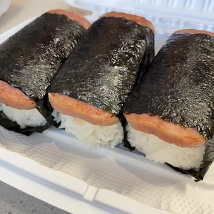 three sushi rolls in a styrofoam container