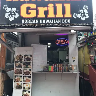 a food stand with a sign that says hawaiian grill
