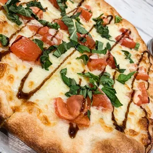 a pizza with tomatoes, basil, and mozzarella