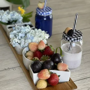 a tray of strawberries, plums, and plums on a table