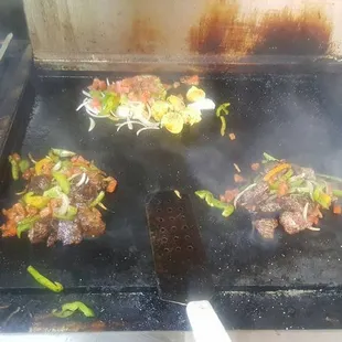a grill with meat and vegetables cooking on it