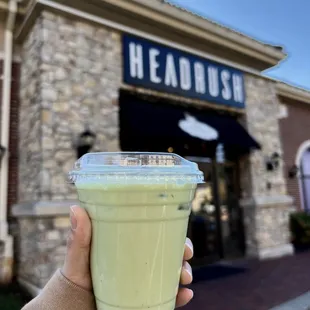a hand holding a cup of green tea