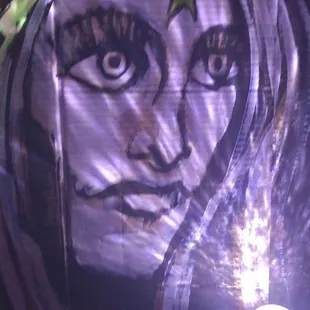 a lit candle in front of a painting of a woman's face