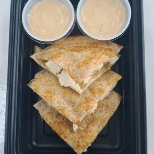 a plate of quesadillas with dips