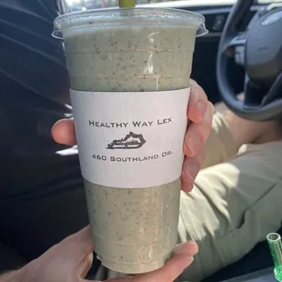 a hand holding a cup of green smoothie