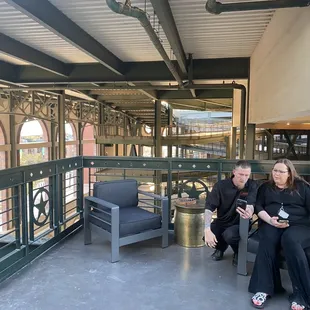 two people sitting on a bench at a train station