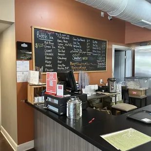 a coffee shop counter with a menu on the wall