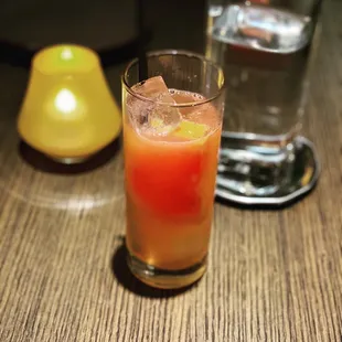 a drink in a glass with ice and a lemon