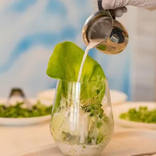 a person pouring dressing into a glass