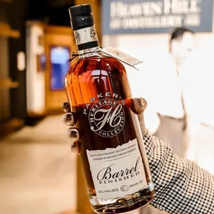 a hand holding a bottle of bourbon