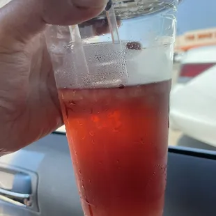 a hand holding a cup of iced tea