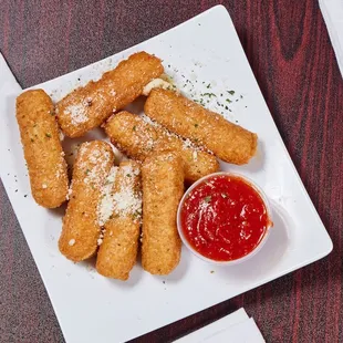 a plate of deep fried pizza sticks with ketchup
