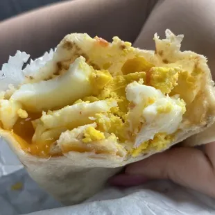 a person holding a breakfast burrito