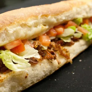 a sandwich with meat, lettuce and tomatoes