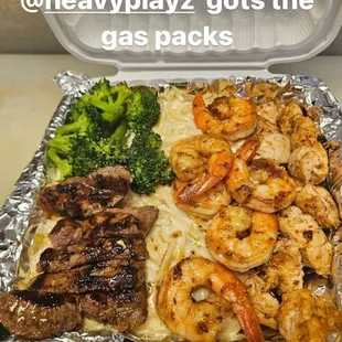 a tray of food that includes shrimp, broccoli, and steak
