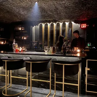 a bar with gold bars and stools