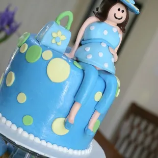 a blue cake with a woman sitting on top of it