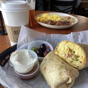 Breakfast burrito and eggs,bacon, hash browns behind! Nice little bowl of fruit and salsa/ sour cream with the burrito.