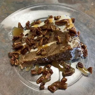 Carrot cake topped with candied pecans and drizzled with caramel sauce.