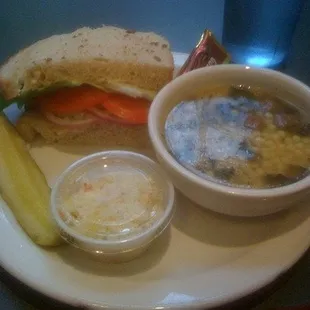 Half soup and sandwich with coleslaw and a pickle.