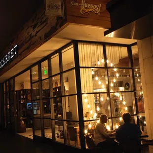 two people sitting outside a coffee shop