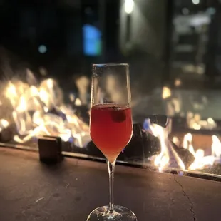 a glass of wine in front of a fireplace