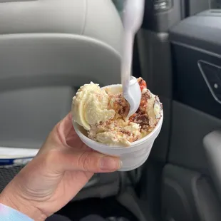 a hand holding a bowl of ice cream