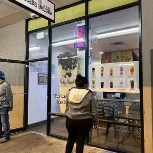 two people standing outside of a coffee shop