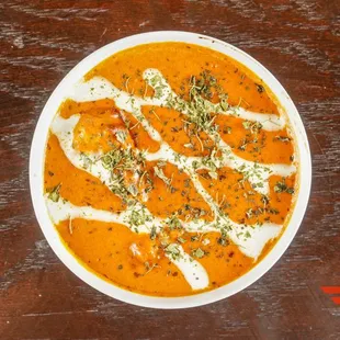 a bowl of carrot soup on a wooden table