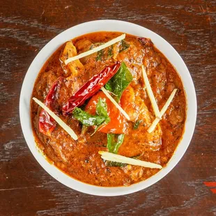 a bowl of chicken curry on a wooden table