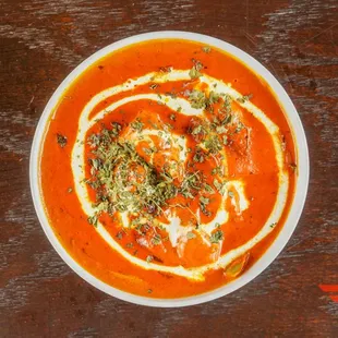 a bowl of tomato soup on a wooden table