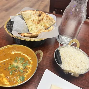 a bowl of curry, a bowl of rice, and a plate of naan bread