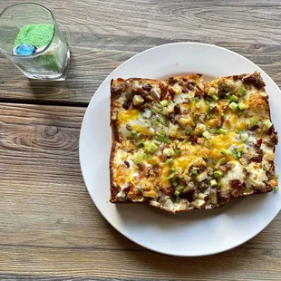 a slice of pizza on a white plate next to a glass of water