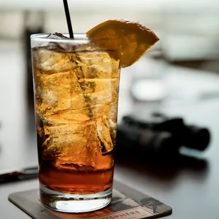 a glass of iced tea with a lemon wedge