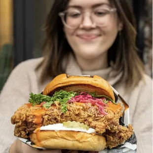 a woman holding a chicken sandwich