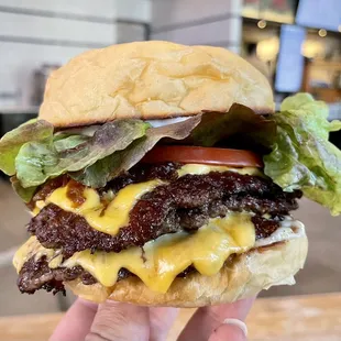 Triple Henbit burger with Peeler Farms Wagyu beef, American cheese, sour pickles, tomatoes, grilled onions, lettuce, and shiitake aioli