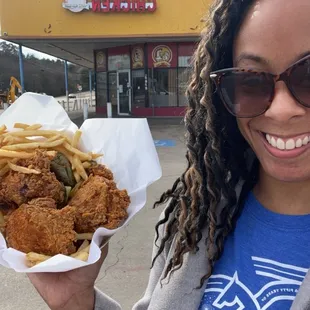 a woman holding a basket of fried chicken