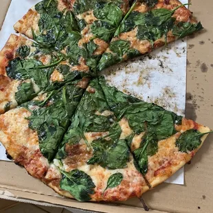 a pizza with spinach and cheese in a box