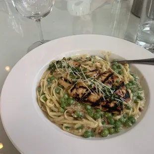 a plate of pasta with chicken and peas