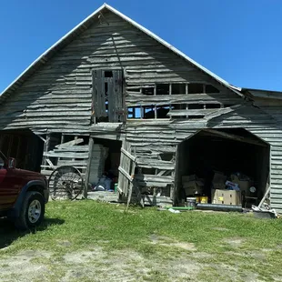 an old barn with a truck parked in front of it