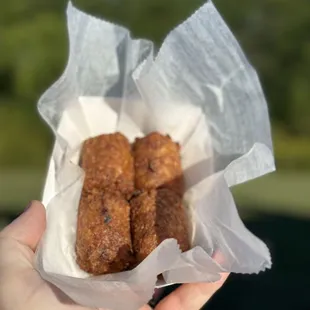a hand holding a basket of chicken nuggies