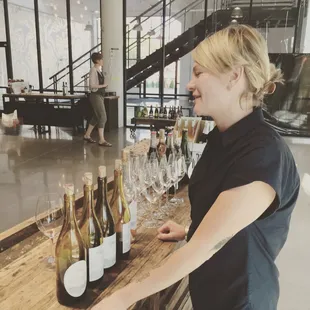 a woman standing in front of a table full of wine bottles