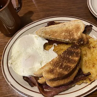 Over easy eggs, bacon, and hash browns with wheat toast