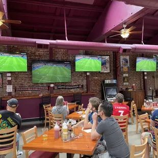 people sitting at tables watching televisions