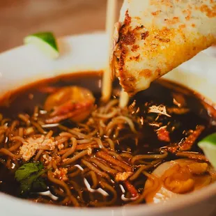 a bowl of noodles and a slice of pizza