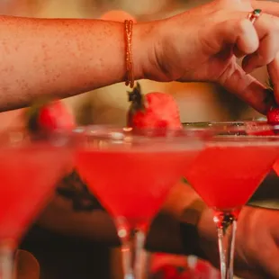 a hand picking a strawberry from a martini