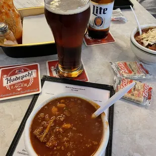 a bowl of chili soup and a glass of beer